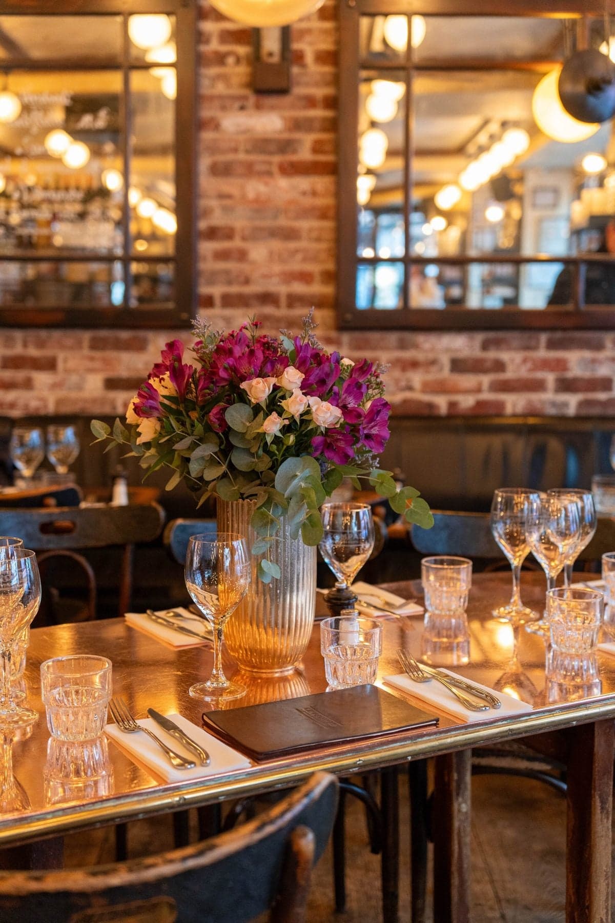 Une table dressée avec un bouquet, des verres et une lumière chaude